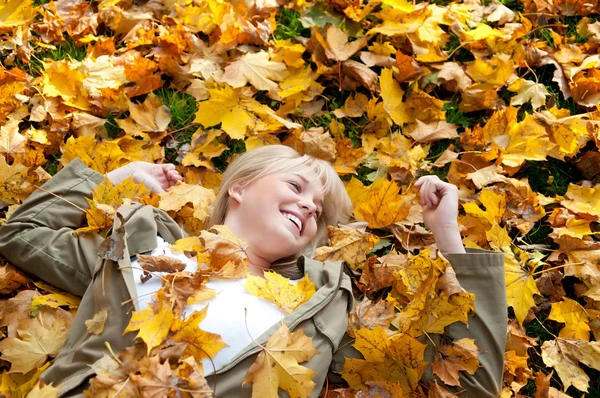 Junge Frau liegt im Herbstlaub — Stockfoto