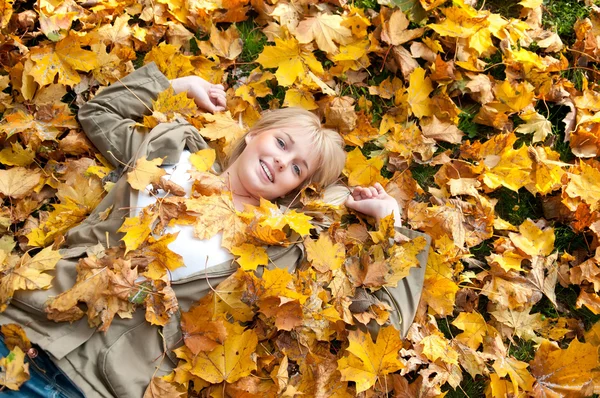Jovem mulher deitada em folhas de outono — Fotografia de Stock