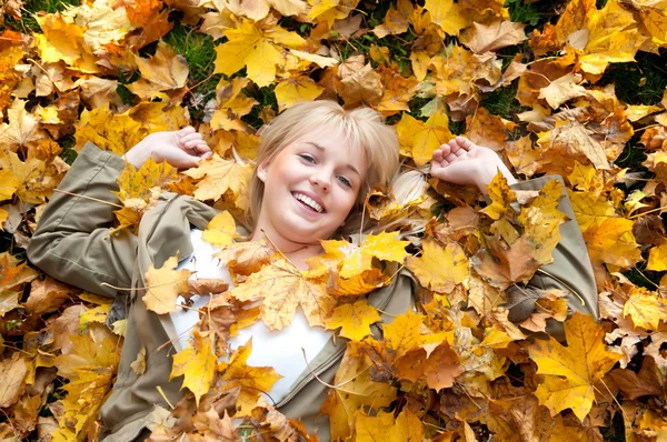 年轻女子躺在秋天的树叶 — 图库照片