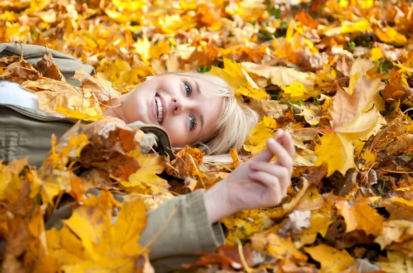 Jovem mulher deitada em folhas de outono — Fotografia de Stock