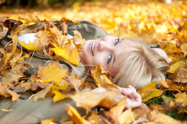 Junge Frau liegt im Herbstlaub — Stockfoto