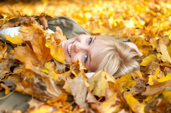 Sonbahar yaprakları yatan genç kadın — Stok fotoğraf