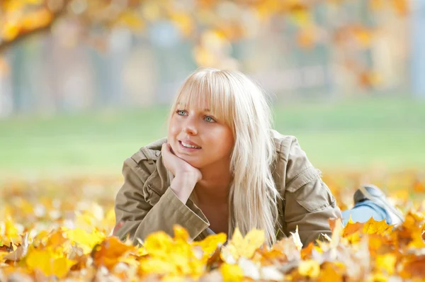 Mujer joven acostada en hojas de otoño — Foto de Stock