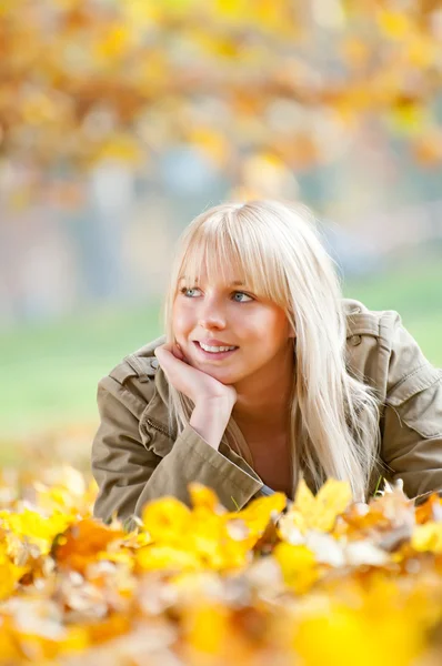年轻女子躺在秋天的树叶 — 图库照片