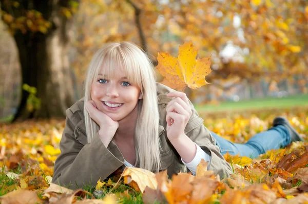 Jonge vrouw liggen in de herfst bladeren — Stockfoto