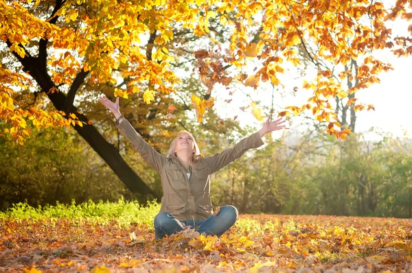 Sonbahar yaprakları ile oynayan genç bir kadın — Stok fotoğraf