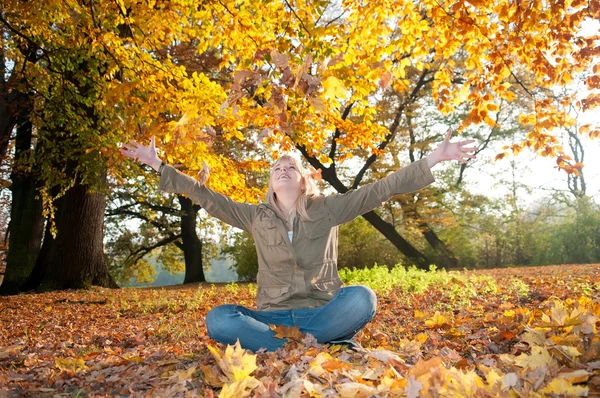 Νεαρή γυναίκα που παίζει με τα Φθινοπωρινά φύλλα — Φωτογραφία Αρχείου
