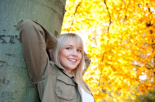 Young woman standing at a tree — Stock Photo, Image