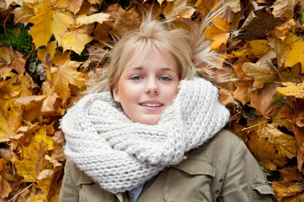 年轻女子躺在秋天的树叶 图库照片