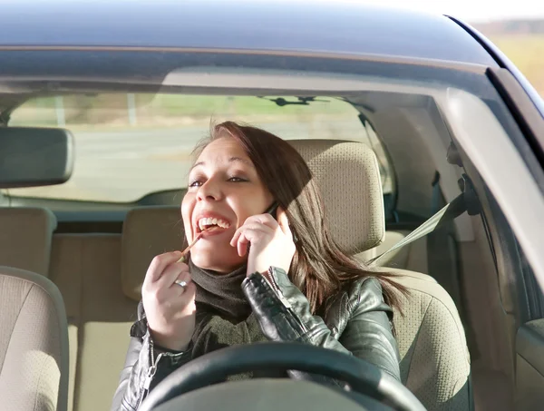 Mujer con lápiz labial y teléfono celular en el coche — Foto de Stock
