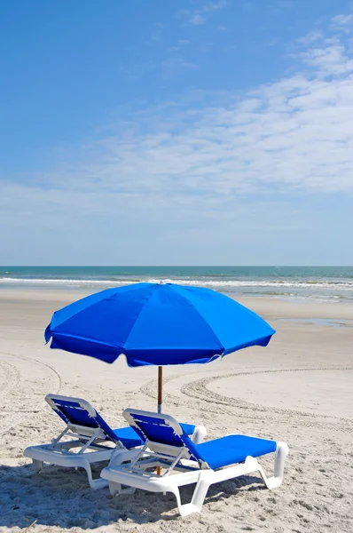 Пляжные стулья с голубыми зонтиками — стоковое фото