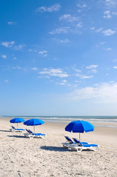 Plaj sandalyeleri ile mavi şemsiye — Stok fotoğraf