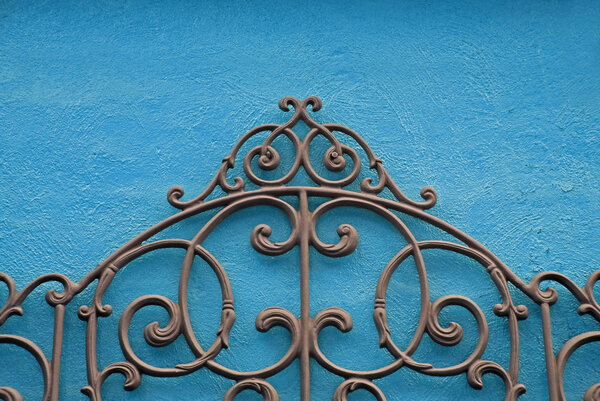 A Decorative Piece of Wrought Iron Mounted to a Bright Colored Stucco Wall