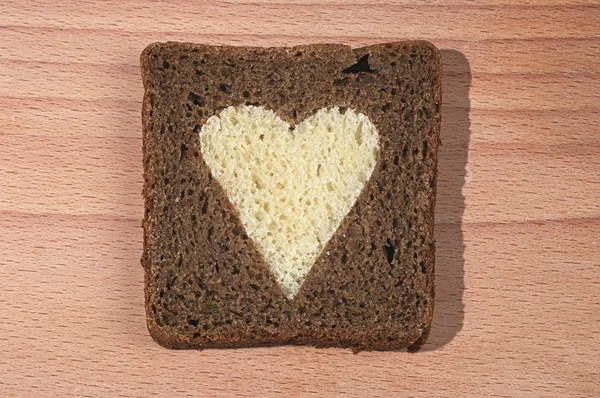 흰색 덩어리에서 심장 밖으로 잘라 갈색 빵의 조각 — 스톡 사진