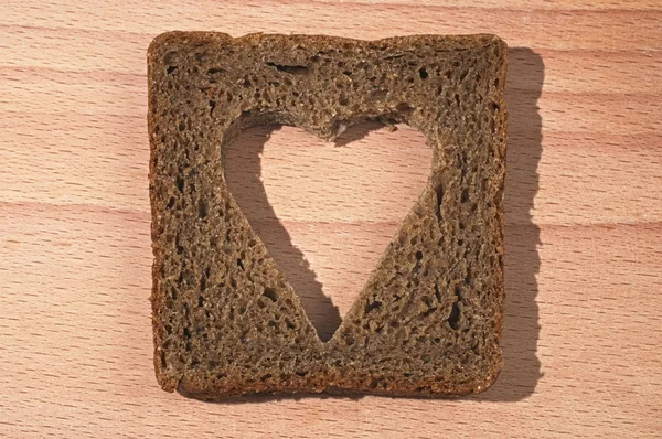El pedazo del pan negro con la pulpa cortada en forma del corazón — Foto de Stock