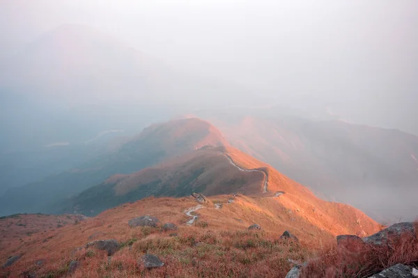 Dark landscape with fog between hills and orange sky before sunr — Stock Photo, Image