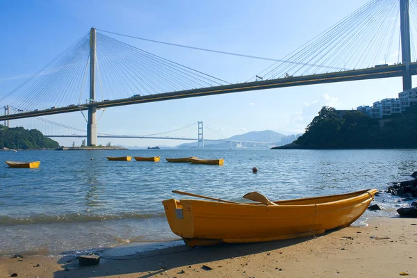 Лодка на пляже под мостом — стоковое фото