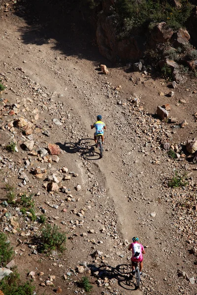 Två cyklister rasing i öknen bergen — Stockfoto