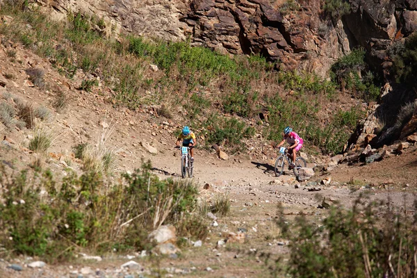 Dos ciclistas rascando en las montañas del desierto — Foto de Stock