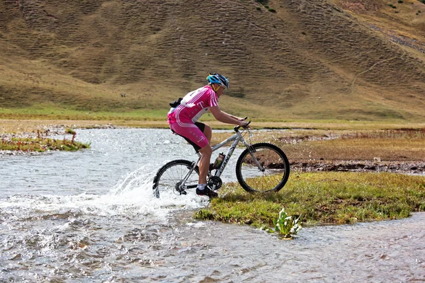 Cyclist at the speed of moving mountain river — Stock Photo, Image