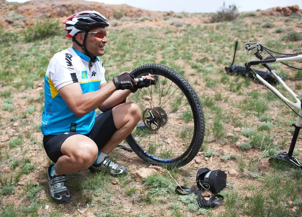 stock image Biker changing a flat tire on desert mountain bike competition