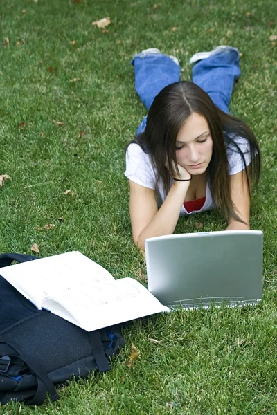 Linda chica adolescente acostada en la hierba estudiando — Foto de Stock