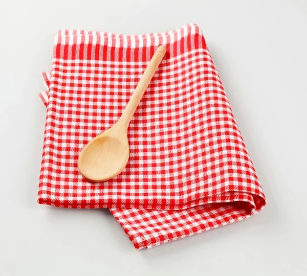 Wooden spoon on tea towel — Stock Photo, Image