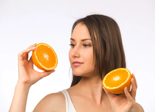 Młoda kobieta trzymając dwie połówki pomarańczy — Zdjęcie stockowe