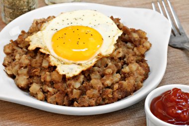 Fried egg on top of roast beef hash. clipart