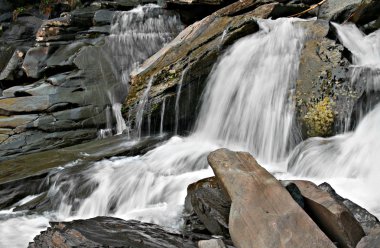 Veiled waterfall in rocky glen in the mountains. clipart