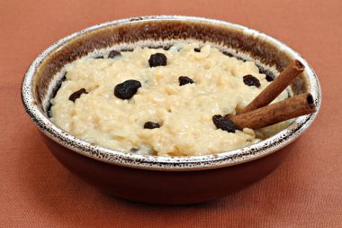 Large bowl of creamy rice pudding with raisins and cinnaomon sti