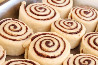Raw cinnamon buns ready to bake with selective focus.