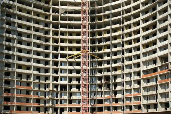 Grúa de construcción en el fondo de un edificio de varios pisos —  Fotos de Stock