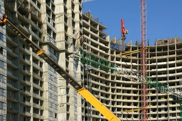Guindaste de construção no fundo de um edifício de vários andares — Fotografia de Stock