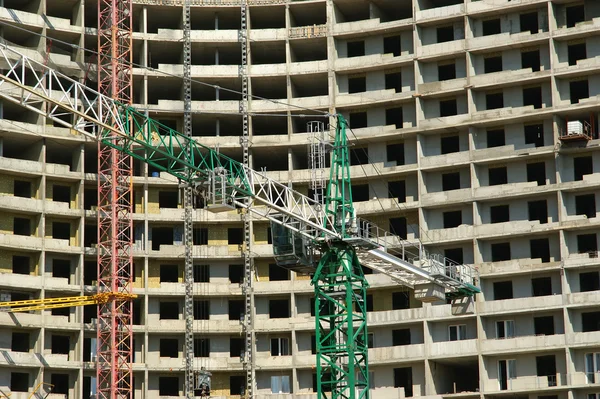 Grúa de construcción en el fondo de un edificio de varios pisos —  Fotos de Stock