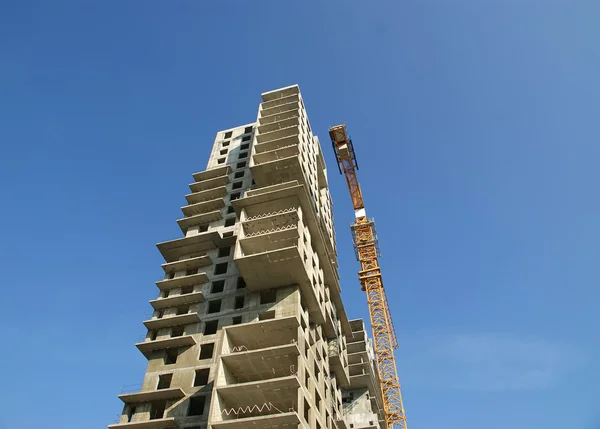 Guindaste de construção no fundo de um edifício de vários andares em construção — Fotografia de Stock