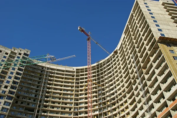Building crane at the background of building under construction — Stock Photo, Image