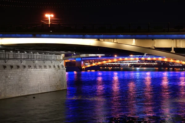 在晚上与反映在水中的光河上的桥梁 — 图库照片