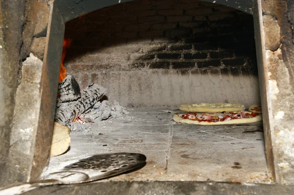 Pizza being baked in a wood fire brick oven — Stock Photo, Image