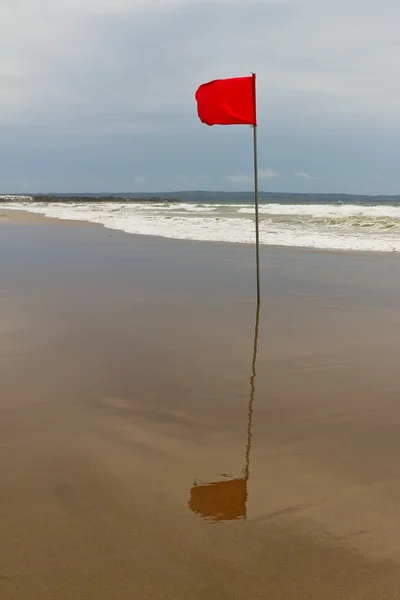 Säsong av stormar. röd flagga på stranden — Stockfoto