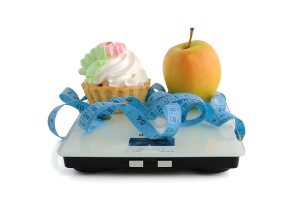 Cake and apple on scales measuring tape wrapped — Stock Photo, Image
