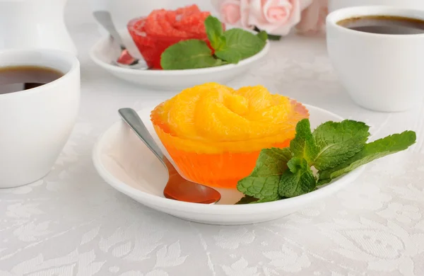 stock image A cup of coffee and orange jelly with slices of fresh orange