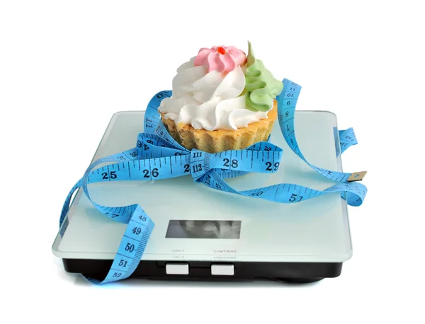 Cake on the scales measuring tape wrapped — Stock Photo, Image