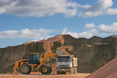 Bulldozer in a gravel pit with truck clipart