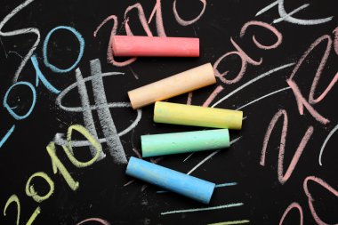 Colorful chalks on the blackboard clipart