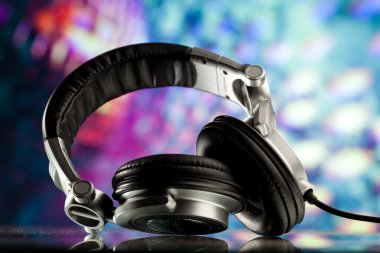 Headphones against purple disco background clipart