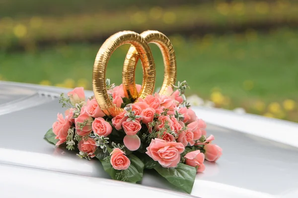 Anéis de casamento no carro com belo monte de flores — Fotografia de Stock