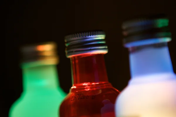 Tři skleněné láhve s barevné osvětlení — Stock fotografie