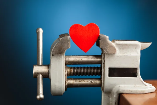 Rött hjärta i ett skruvstäd verktyg — Stockfoto