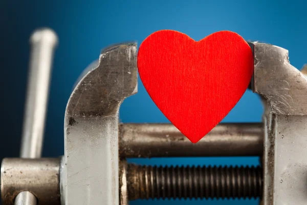 Rött hjärta i ett skruvstäd verktyg — Stockfoto